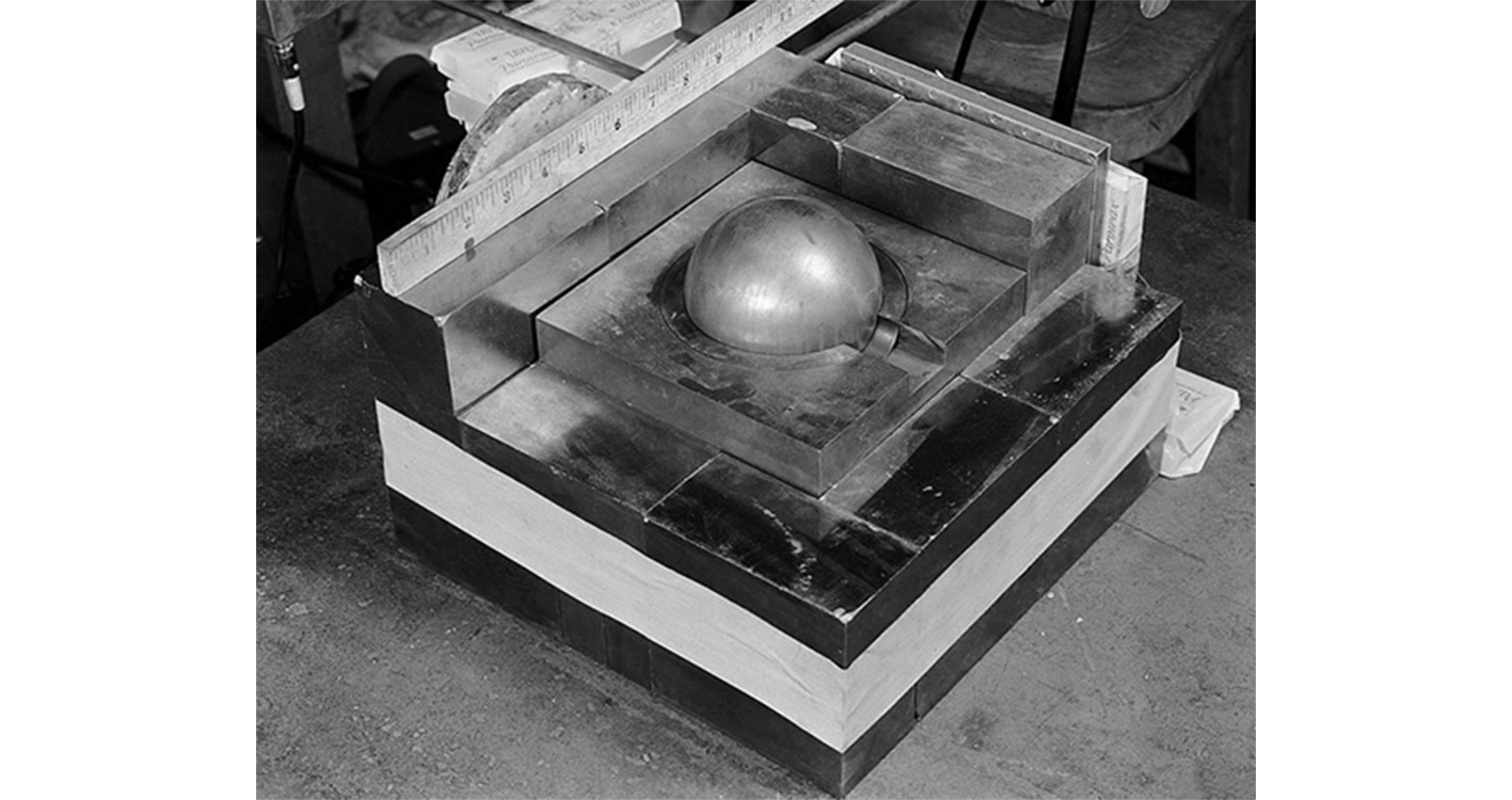 A mockup of a sphere of plutonium sitting in a square of another metal.
